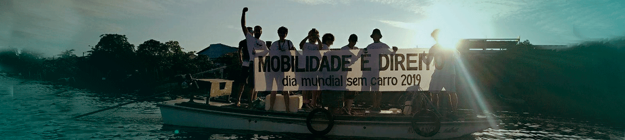 Várias pessoas associadas ameciclo segurando uma faixa que diz Dia Mundial Sem Carro em cima de um barco no rio capibaribe