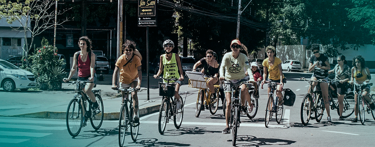 Várias mulheres (11) de bicicleta andando na rua ocupando duas faixas e atravessando um cruzamento
